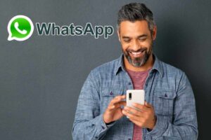 uomo con smartphone e logo whatsapp