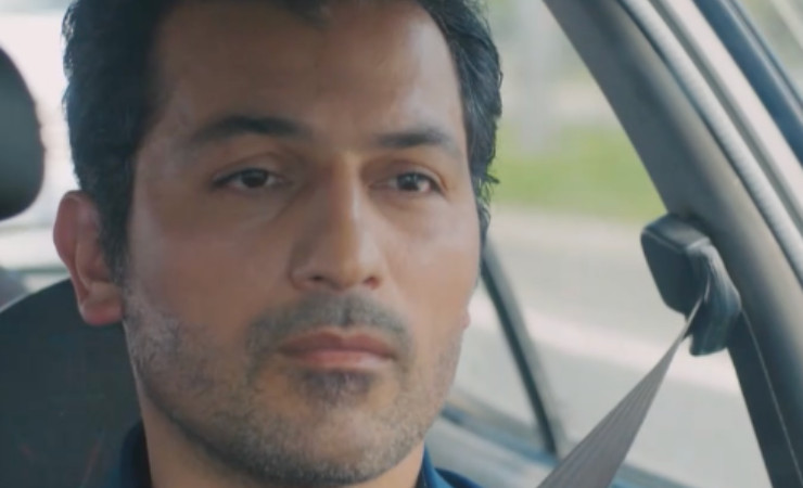 Arif con espressione seria che guida