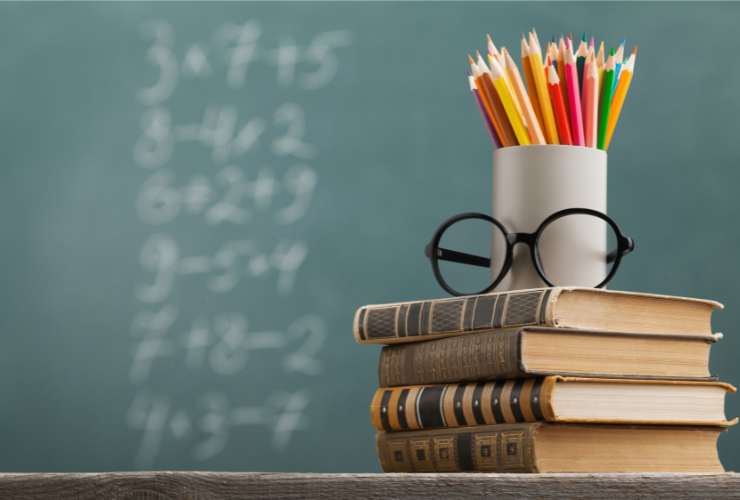 lavagna in classe, libri, matite e occhiali