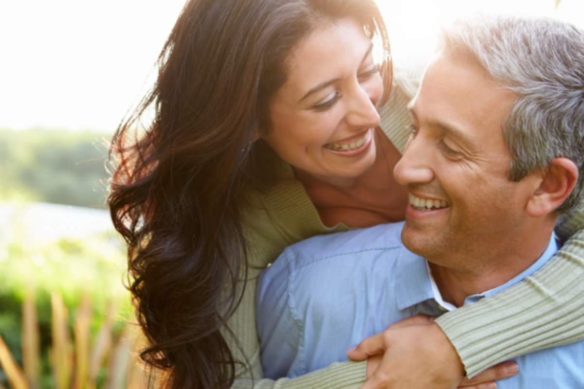 donna che sorride e abbraccia un uomo da dietro
