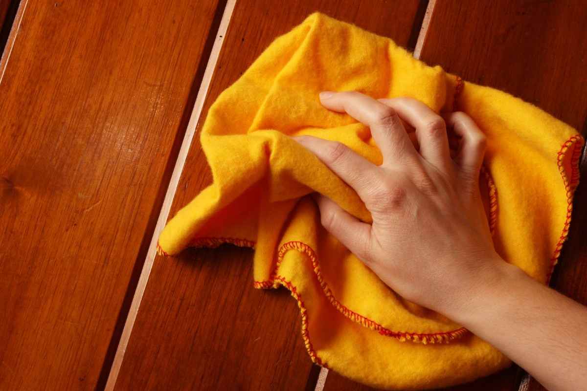 persona passa un panno su una superficie di legno