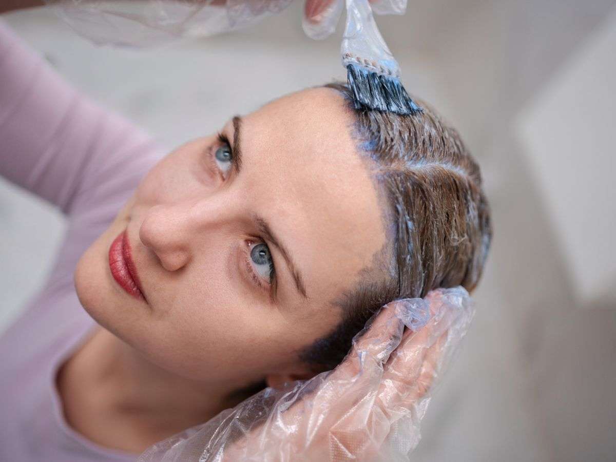 donna applica tinta sui propri capelli
