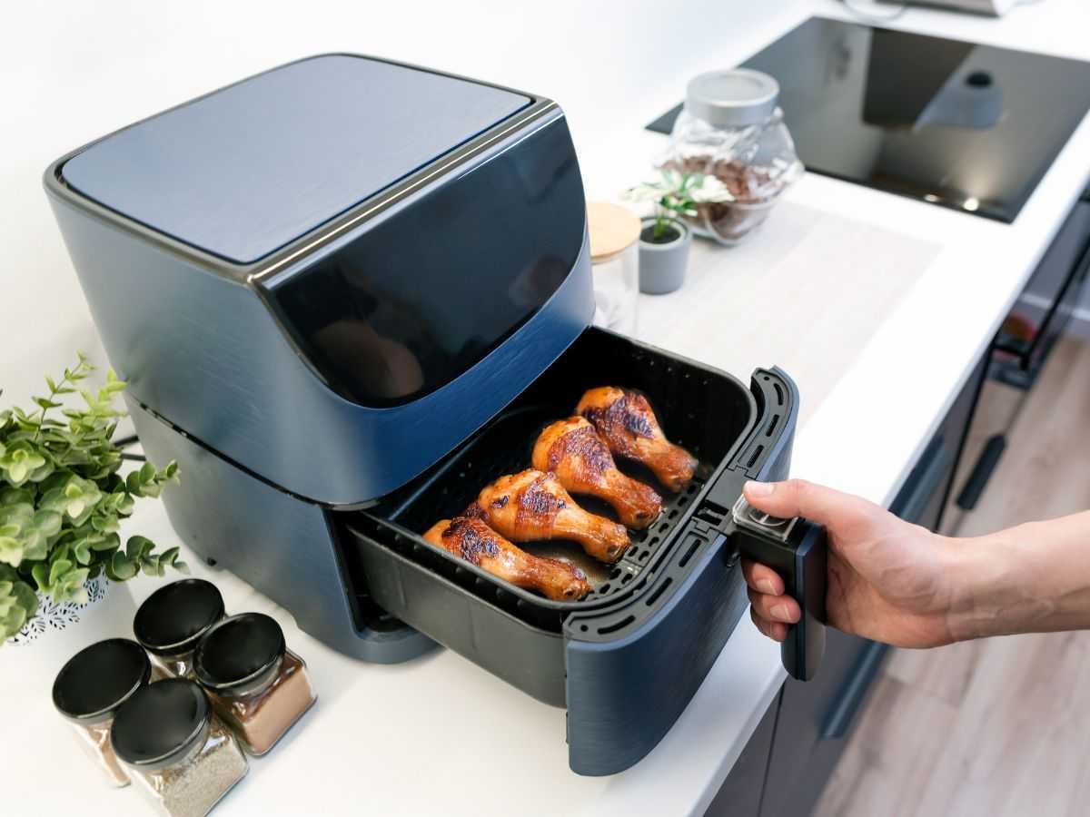 una friggitrice ad aria con il cestello pieno di cosce di pollo