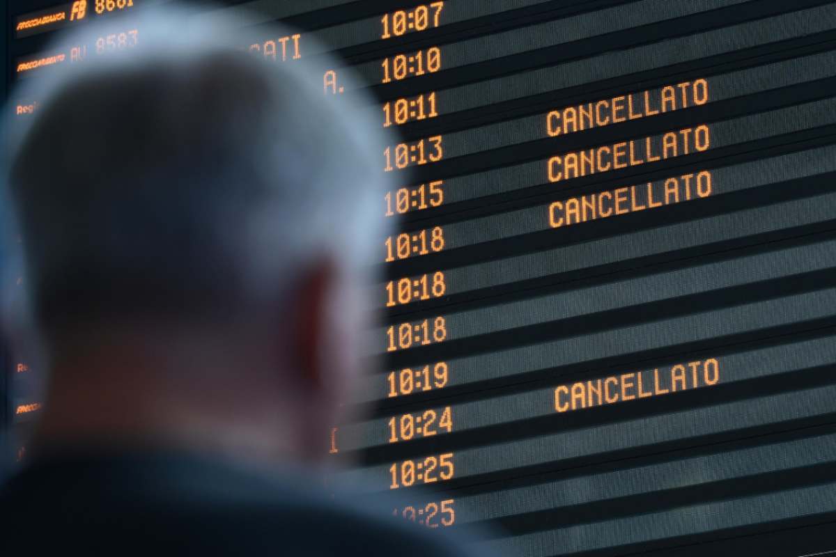 uomo che osserva tabellone orari treni