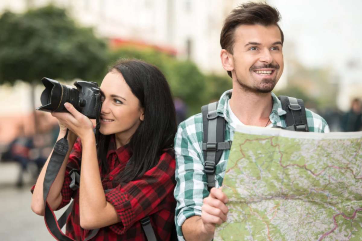 donna con la macchina fotografica e uomo con una cartina geografica