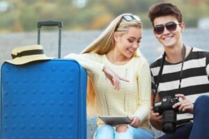 uomo e donna che sorridono con accanto un trolley