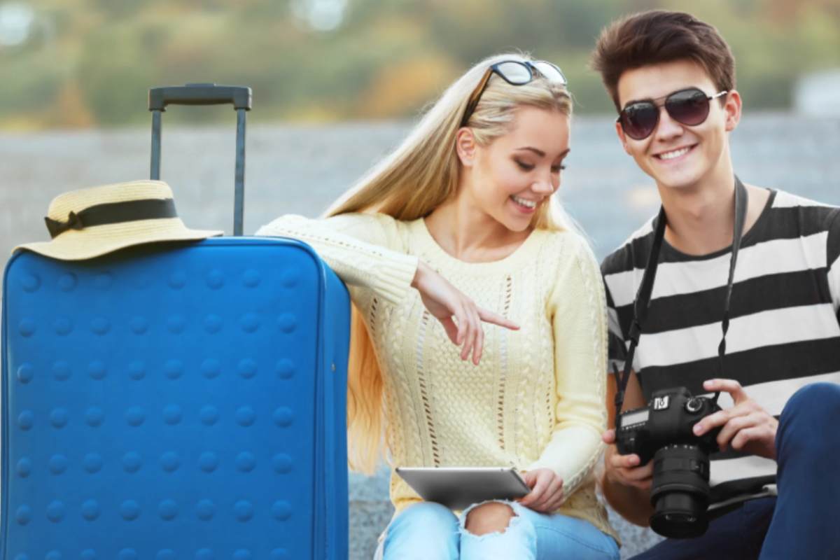 uomo e donna che sorridono con accanto un trolley
