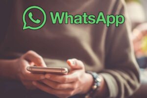 persona con smartphone in mano e logo whatsapp